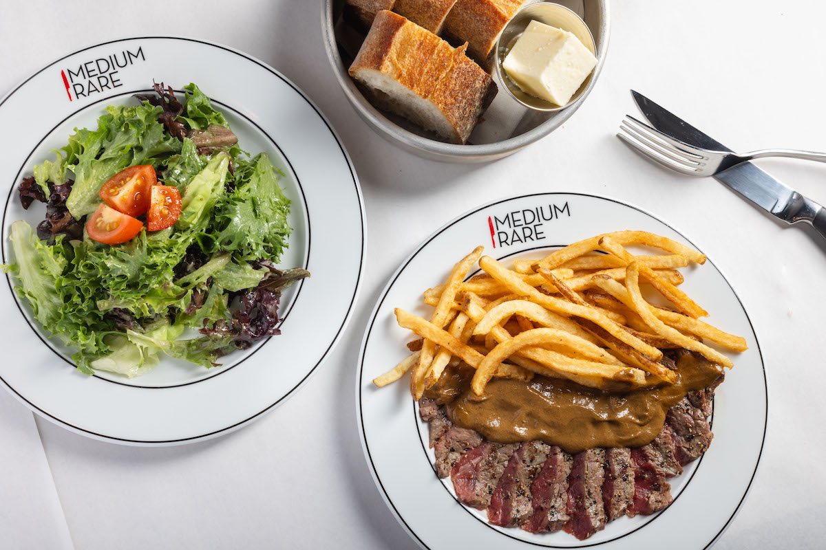 Steak with fries, mixed greens, and bread at Medium Rare. | Photo by Medium Rare