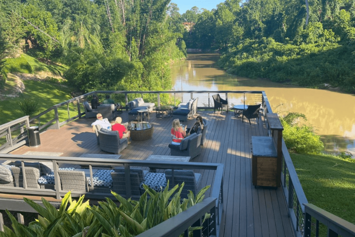 Brenner’s on the Bayou outdoor patio with riverside deck, lounge seating, lush greenery, and scenic bayou views perfect for dining or private events.