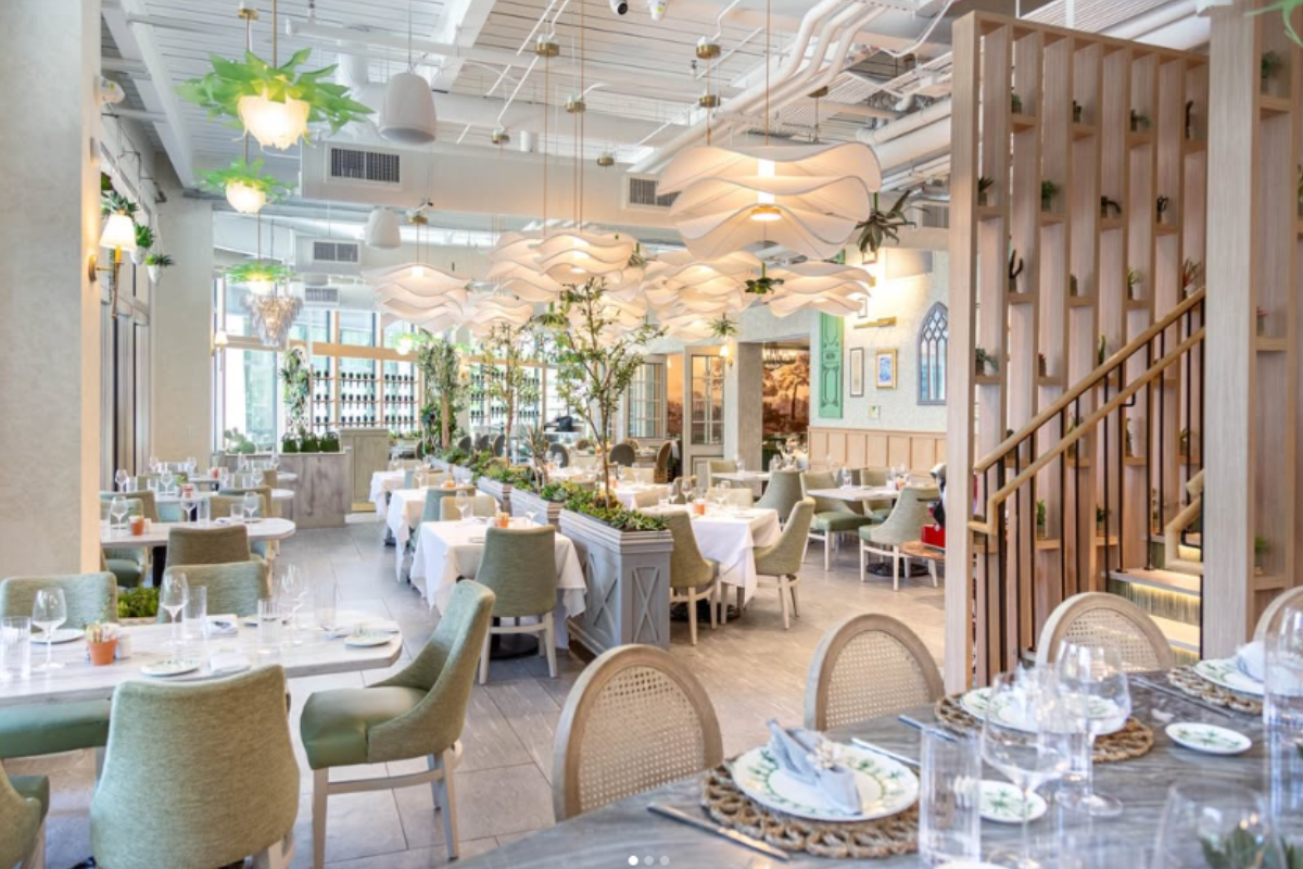 Succulent Fine Dining interior with modern white lighting, green chairs, white tablecloths, wood decor, plants, and elegant, airy atmosphere.